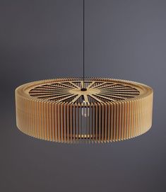 a circular wooden light fixture hanging from a metal ceiling rod with an intricate design on it