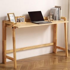 a laptop computer sitting on top of a wooden desk next to a clock and other items