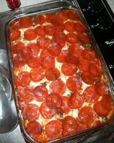 pepperoni and cheese pizza in a baking dish on the stove top next to a measuring spoon