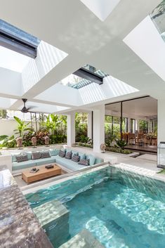 an indoor swimming pool in the middle of a living room with skylights above it