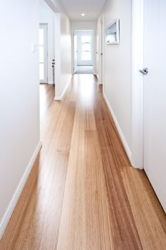 an empty hallway with wood floors and white walls