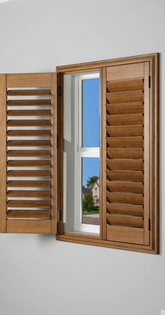 an open window with wooden shutters and white walls