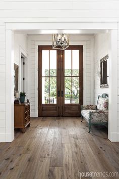 an entryway with wood floors and white painted walls is flanked by a wooden door that leads to another room