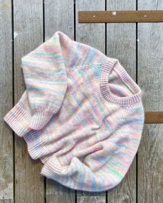 a baby sweater laying on top of a wooden floor