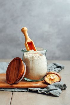 a wooden spoon sitting next to a jar filled with white powder and an orange slice