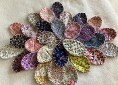 a bunch of colorful plates sitting on top of a white table covered in cloths