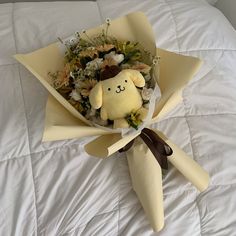 a stuffed animal in a bouquet on a bed