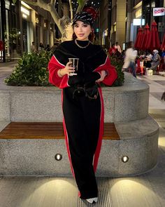 a woman standing next to a bench holding a cup