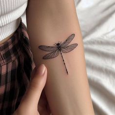 a woman's arm with a small tattoo of a dragonfly on the wrist