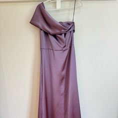 a purple dress hanging on a hanger in a room next to a white wall