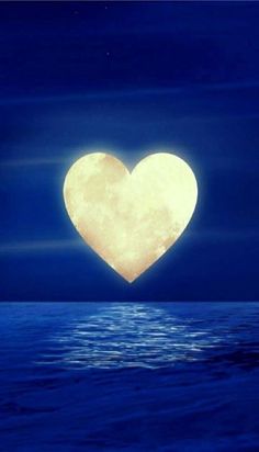 a large heart shaped object floating in the air over water at night with full moon behind it