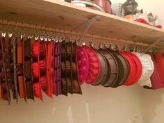 a shelf filled with lots of different colored pots and pans hanging from it's hooks