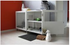 a small white dog sitting on the floor in front of a cabinet with its door open