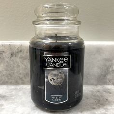 a yankee candle is sitting on a marble countertop in front of a white wall