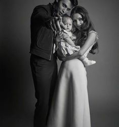 two women and a man are posing for a black and white photo with a baby