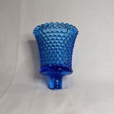 a blue glass vase sitting on top of a white table