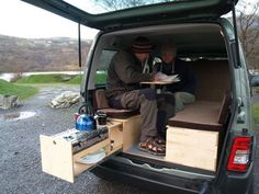 two people sitting in the back of a van