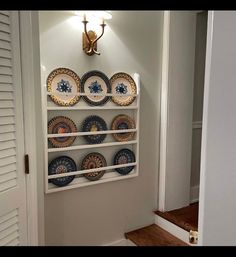 there is a shelf with plates on it in the hallway next to some stairs and a door