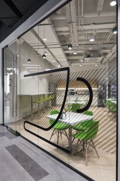 an office with glass walls and tables in the center, surrounded by green chairs that have been placed on top of each other