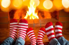 two people wearing red and white striped socks sitting in front of a fire place with their feet up