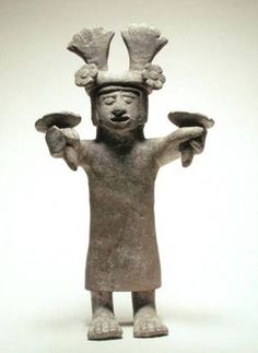 an ancient figurine is holding two hands up to his head and wearing a hat