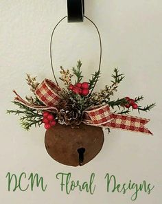 a christmas ornament hanging on the side of a wall with pine cones and berries