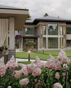 a large house with lots of windows and flowers in the front yard