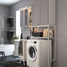 a washer and dryer in a small room with grey tile flooring on the walls