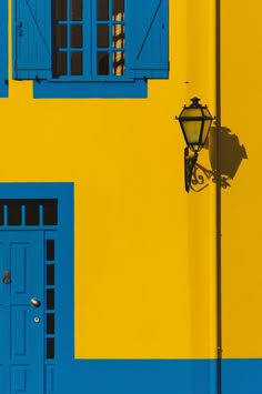 a yellow and blue building with two doors on each side, one has a light fixture in front of it