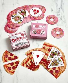 a table topped with pizza slices and playing cards next to donuts on top of each other