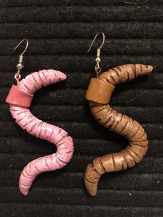 two wooden earrings with pink and brown beads on black background, one is shaped like a worm