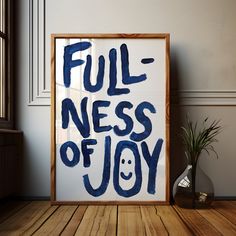 a poster with the words fullness of joy written in blue ink on a wooden floor next to a potted plant