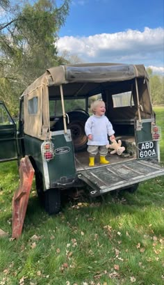 a little boy that is standing in the back of a truck with a stuffed animal