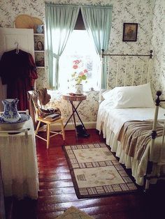 a bed room with a neatly made bed next to a chair and a rug on the floor