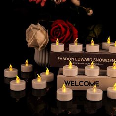 there are many lit candles in front of a box with the name welcome on it