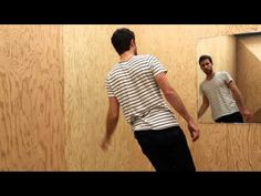 a man standing in front of a mirror with his reflection on the wall behind him