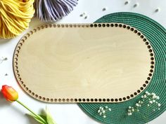 a wooden plate with beaded trim on it next to some yarn and tulips