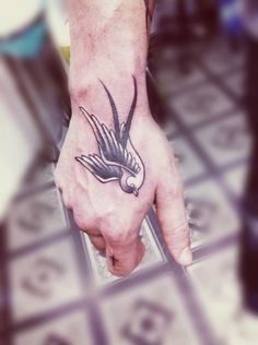 a hand with a bird tattoo on it