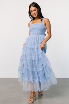 a woman is wearing a blue dress with tiered ruffles on the bottom