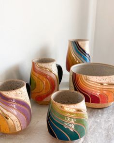 five different colored bowls sitting on top of a white counter next to each other,