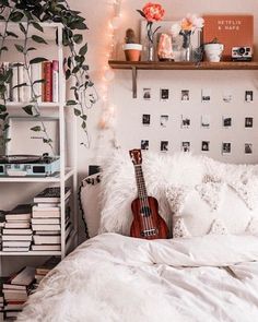 a bed with a guitar on it in a room filled with books and other items