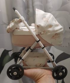 a hand holding a baby stroller in front of a curtain