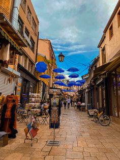 an alley way with umbrellas and shops on both sides