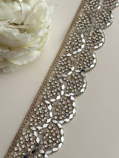 a white flower sitting next to a silver belt on top of a table with flowers