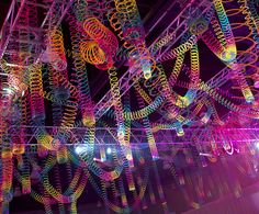 an art installation is lit up at night with colorful lights and spirals hanging from the ceiling