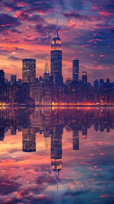 the city skyline is reflected in the water at sunset with clouds reflecting on the water