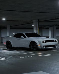 a white sports car parked in a parking garage with no one around it at night