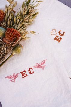 two embroidered napkins with flowers on them sitting next to each other and the words peace written in red