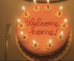 a welcome home cake with lit candles on it