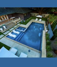 an aerial view of a backyard with a swimming pool and lounge chairs in the foreground